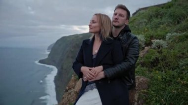 Romantik çift uçurumun kenarında, okyanusun nefes kesici manzarasının tadını çıkarıyorlar.