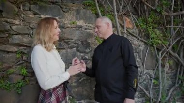 Madeira, Portekiz 'deki taş bir duvarın yanında el ele tutuşup birbirlerine bakan romantik bir çift.