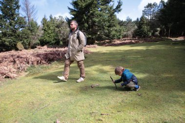 Baba ve oğul ormanda rahatça yürüyüp aile bağlarını ve açık hava aktivitelerini destekliyor.