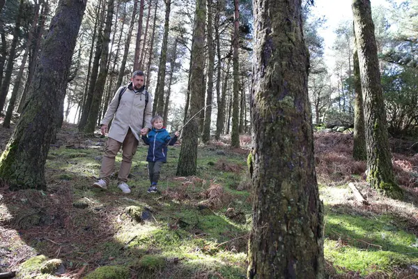 Baba ve oğul canlı yeşil yosunlarla kaplı sakin bir orman yolunda sakin bir yürüyüş yapıyorlar.