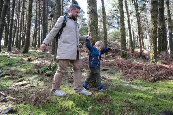 Baba ve oğul yemyeşil bir ormanda yürüyüş yapıyorlar.