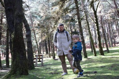 Baba ve oğul güneşli bir ormanda sakin bir yürüyüş yapıyorlar.