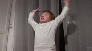 Çocuk perdelerin önünde yorumlayıcı bir dans sergiler.