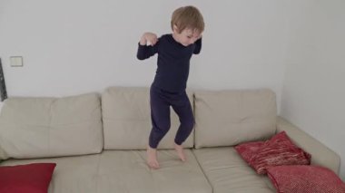 Küçük çocuk rahat bir kanepede zıplayıp zıplamaktan hoşlanıyor.