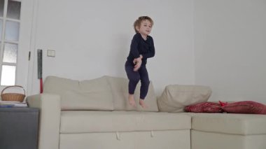 Neşeli çocuk atlıyor ve rahat bir kanepede eğleniyor.