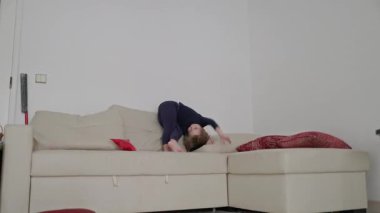Enerjik çocuk, rahat bir oturma odasında rahat bir kanepede zıplayıp yuvarlanmaktan zevk alıyor.