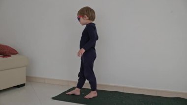 Minderde güneş gözlükleriyle dans eden küçük bir çocuk.