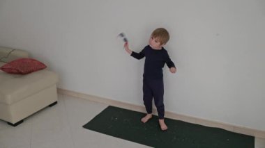 Çocuk minimalist bir ortamda yoga minderinde dans alıştırması yapıyor.