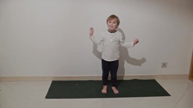 Yoga minderinde dans eden çocuk, beyaz bir arka planda izole edilmiş.