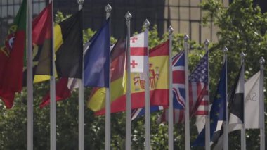 Modern bir binanın önünde çeşitli ulusal bayraklar sallanıyor.