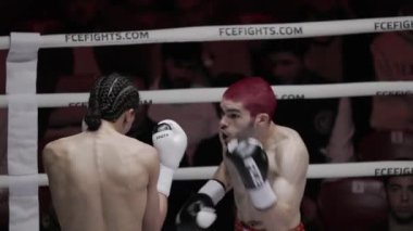 8 Mayıs 2025, Lizbon, Portekiz kickboks müsabakası yoğun muay thai karşılaşması kızıl saçlı kickboksörlerin rakibine karşı güçlü vuruşlarını gösteriyor.