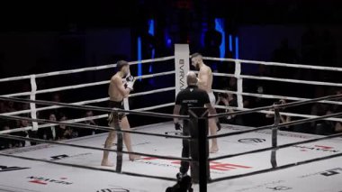 8 Mayıs 2025, Lizbon, Portekiz kickboks müsabakası iki kickboksçu, hakemin dikkati altında birbirlerine güçlü tekme ve yumruklaşmalar yapıyorlar.