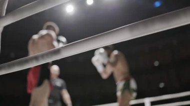 İki Muay Thai dövüşçüsü sert bir dövüşte, güçlü tekmeler ve yumruklaşıyorlar.