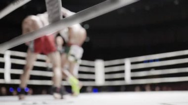 İki Muay Thai dövüşçüsü bir boks ringinde, bir dizi yumruk ve tekme yumruklaşıyorlar.