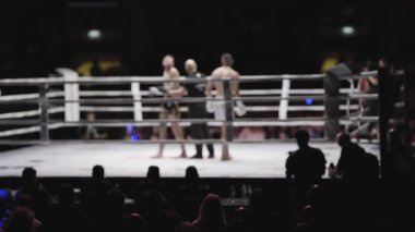 Kickboxerlar bir ringde yarışıyor, kalabalık tarafından izleniyor.