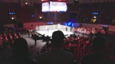 İnsanlar büyük bir arenada boks maçı izliyor.