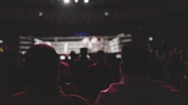 İki seyirci büyük bir arenada boks maçı izliyor.