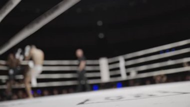 Boksörler ringin kenarından görülen bulanık bir boks maçında dövüşüyor.