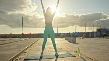 Spor salonundaki kadın paspasın üzerinde egzersiz yapıyor.