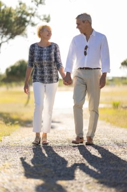 Gülümseyen son sınıf çifti kırsalda birlikte yürüyüş yapıyor.