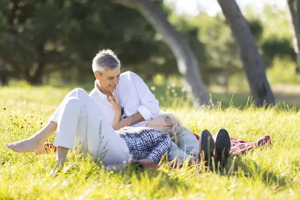Mutlu emekli çift parkta romantik bir pikniğin tadını çıkarıyor, özel anlarını ve altın yıllarını paylaşıyorlar.