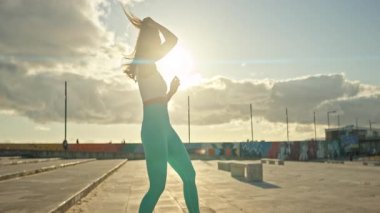 Genç bir kadın gün batımında çatıda antrenman yapmak için hazırlanıyor.