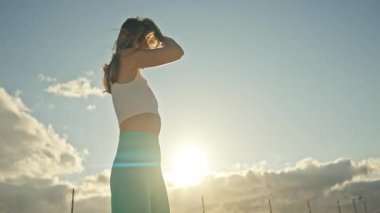 Genç sporcu kadın gün batımında dışarıda antrenman yaptıktan sonra dinleniyor.