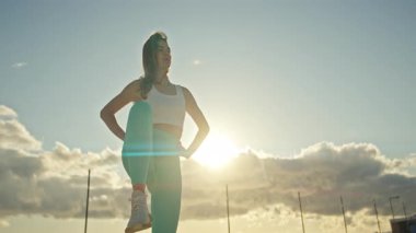 Genç kadın bacaklarını açıyor, altın saat boyunca antrenmana hazırlanıyor.