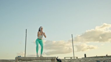 Gökyüzüne karşı antreman yaparken beton blokta kutu atlayışı yapan kararlı sporcu kadın.