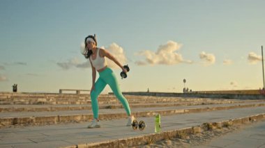 Spor salonundaki kadın dışarıda halterli sıra egzersizi yapıyor.