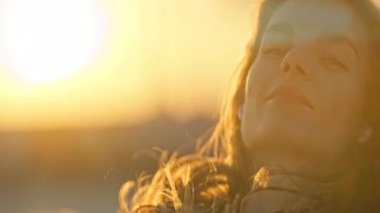 Gün batımında kulaklıklarla müzik dinleyen genç bir kadın, kendini rahat ve mutlu hissediyor.