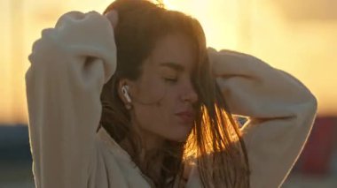 Çekici genç bir kadın kaygısız hissediyor, altın saat güneş ışığının tadını çıkarıyor.