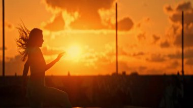 Gün batımında dans eden bir kadın, güzel bir siluet.