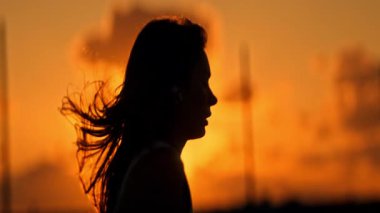 Kadın silueti altın saat günbatımının keyfini çıkarıyor