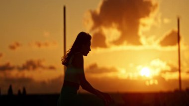 Güzel bir gün batımına karşı ısınan sporcu kadın silueti.