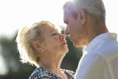 Kıdemli çift sıcak gün ışığında birbirlerine sevgi ve sevgiyle bakıyorlar.