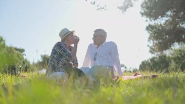 Kıdemli çift güneşli bir parkta piknik yaparken keyifli bir sohbet yapıyorlar.