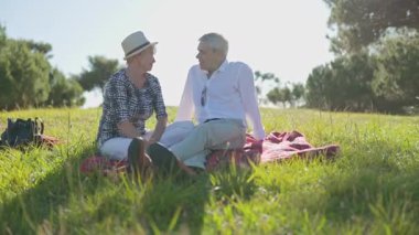Mutlu emekli çift güneşli bir parkta piknik yapıyor.