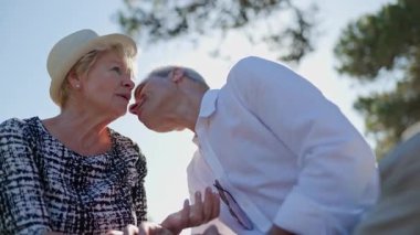 Yaşlı çift romantik bir günün tadını çıkarıyor. Konuşuyorlar, öpüşüyorlar ve güneşli bir parkta birlikte vakit geçiriyorlar.