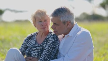 Güneşli bir arazide sevgi gösteren yaşlı bir çift.