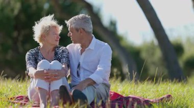 Yaşlı çift güneşli bir parkta romantik bir piknik yapıyor.