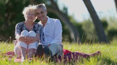 Mutlu emekli çift parkta dinleniyor, güneşli günün tadını çıkarıyorlar.