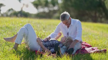 Kıdemli çift, doğada rahatlatıcı bir günün tadını çıkarıyor, kahkahalar ve şefkat paylaşıyorlar.