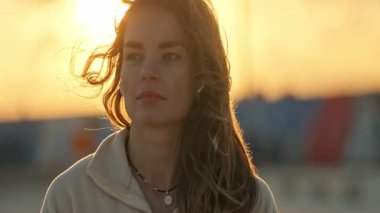 Kablosuz kulaklıklı güzel kadın rüzgarlı bir altın saat günbatımının tadını çıkarıyor.