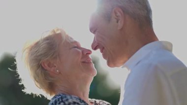 Mutlu yaşlı çift açık havada hassas bir anı paylaşıyor.
