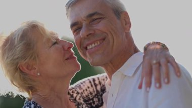 Mutlu yaşlı çift açık havada hassas bir anı paylaşıyor.