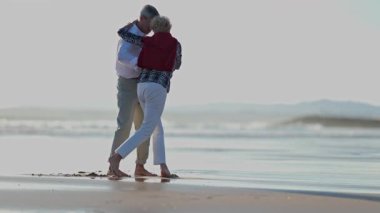 Yaşlı bir çift emekliliğin tadını çıkarıyor, sahilde dans ediyor.