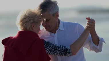 Romantik olgun çift sahilde tango basamaklarının keyfini çıkarıyor.