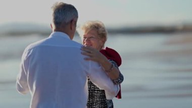 Yaşlı çift sahilde romantik bir dansın tadını çıkarıyor.