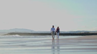 Yaşlı çift sahilde romantik bir yürüyüş yapıyor.